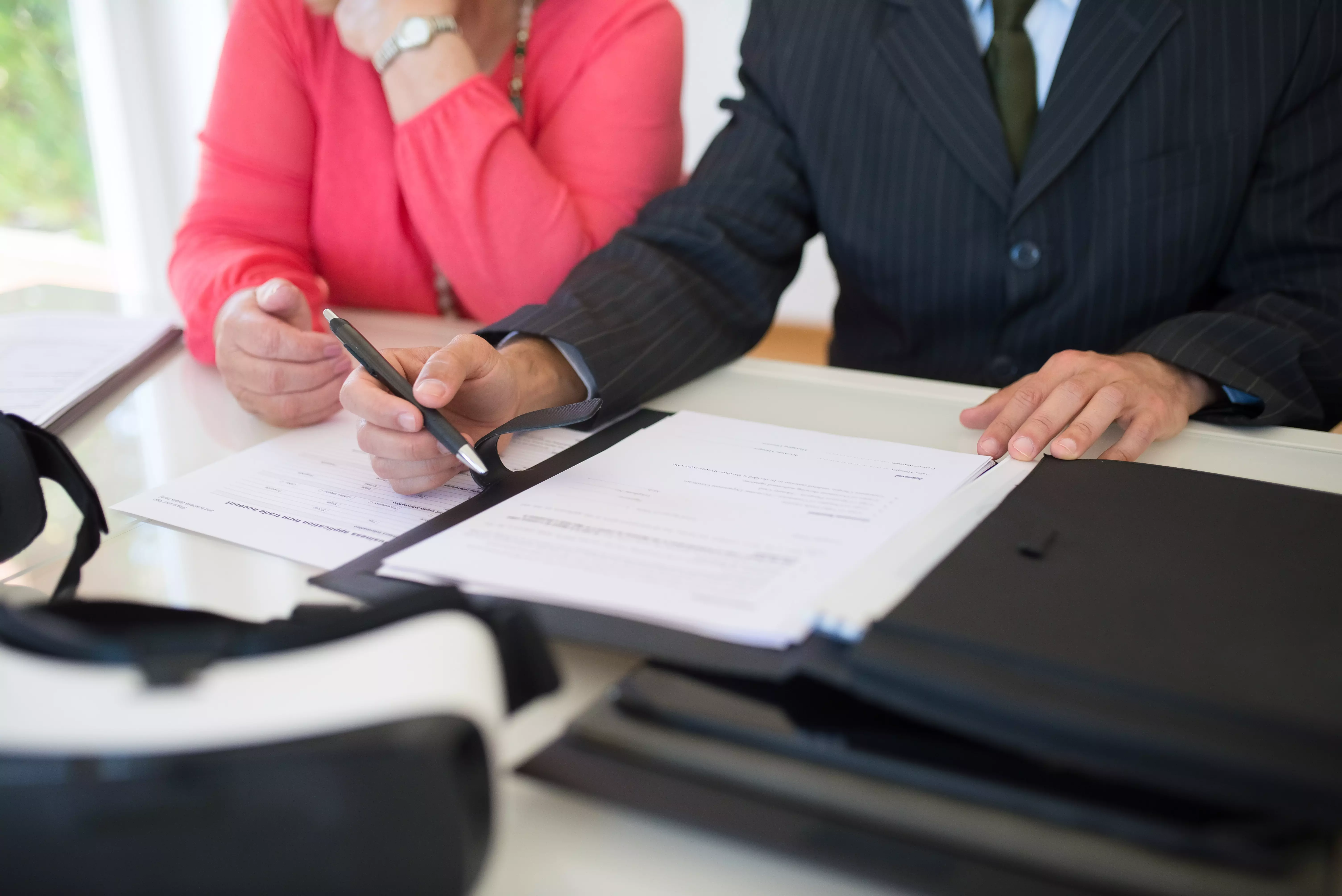 um homem e uma mulher sentados na mesa com uma caneta e um contrato